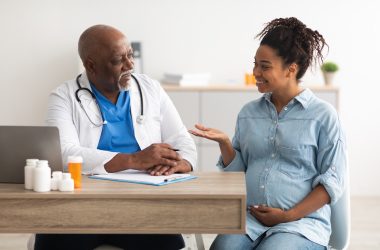 Male doctor consulting young smiling pregnant woman